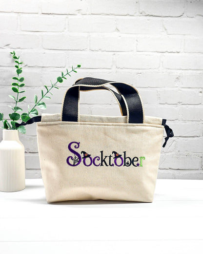 Stricktasche Alva S aus hellem Canvas mit besticktem Socktober-Schriftzug, Hexenhüten und Spinnennetz, handgenäht in Bayern von NadelMikado