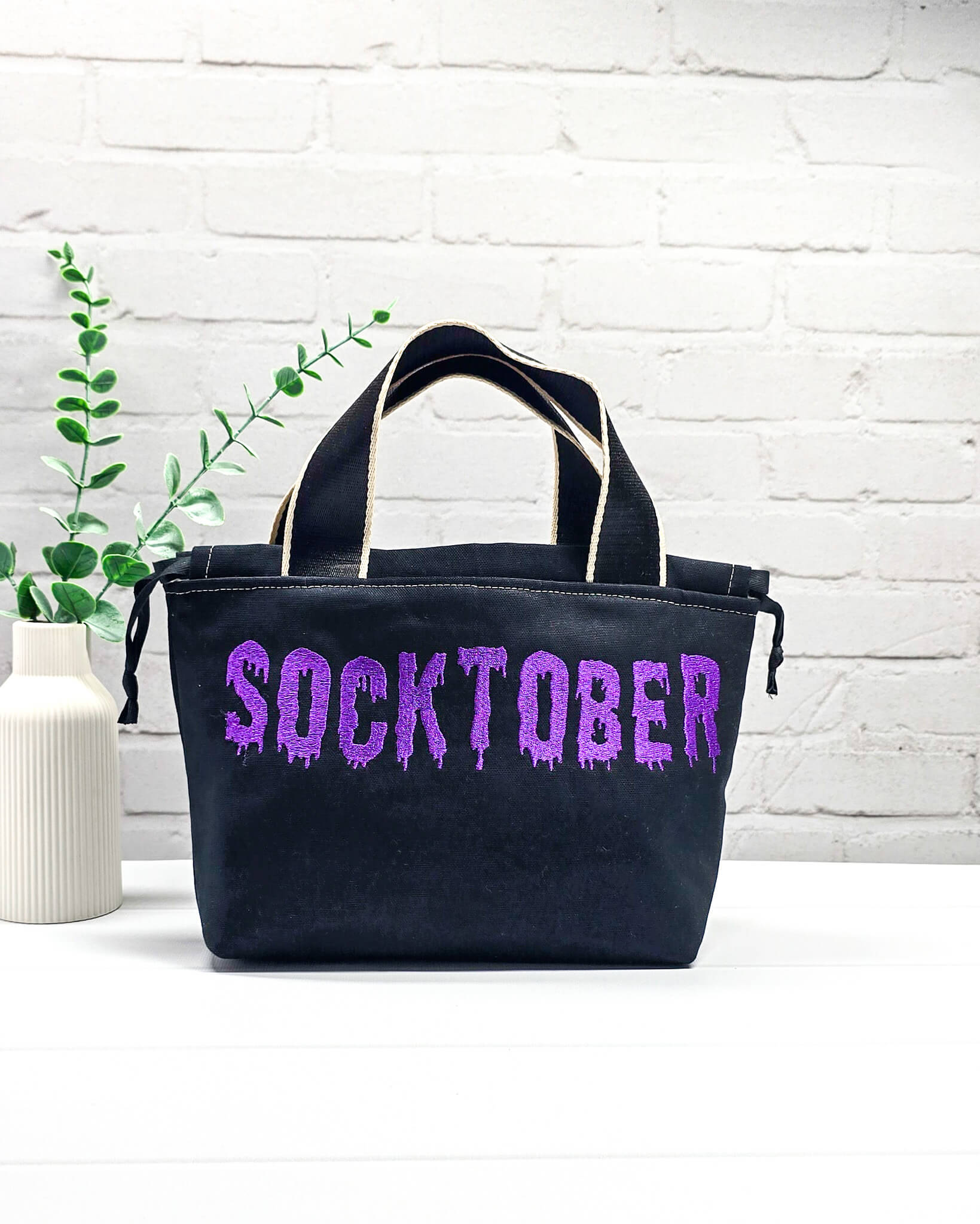 Schwarze Stricktasche Alva S mit violettem Socktober-Schriftzug, handgenäht und bestickt in Bayern von NadelMikado