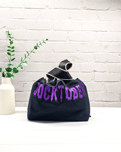 Schwarze Stricktasche Alva S mit violettem Socktober-Schriftzug, handgenäht und bestickt in Bayern von NadelMikado
