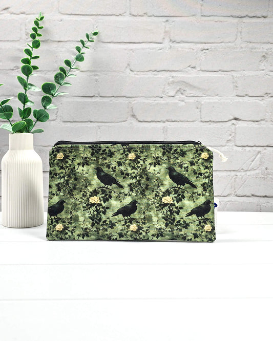 Grüne Tasche mit Reißverschluss, gemustert mit Raben und Rosen, genutzt für Handarbeitszubehör. Handgenäht in Bayern von Nadelmikado.