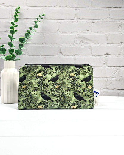 Grüne Tasche mit Reißverschluss, gemustert mit Raben und Rosen, genutzt für Handarbeitszubehör. Handgenäht in Bayern von Nadelmikado.