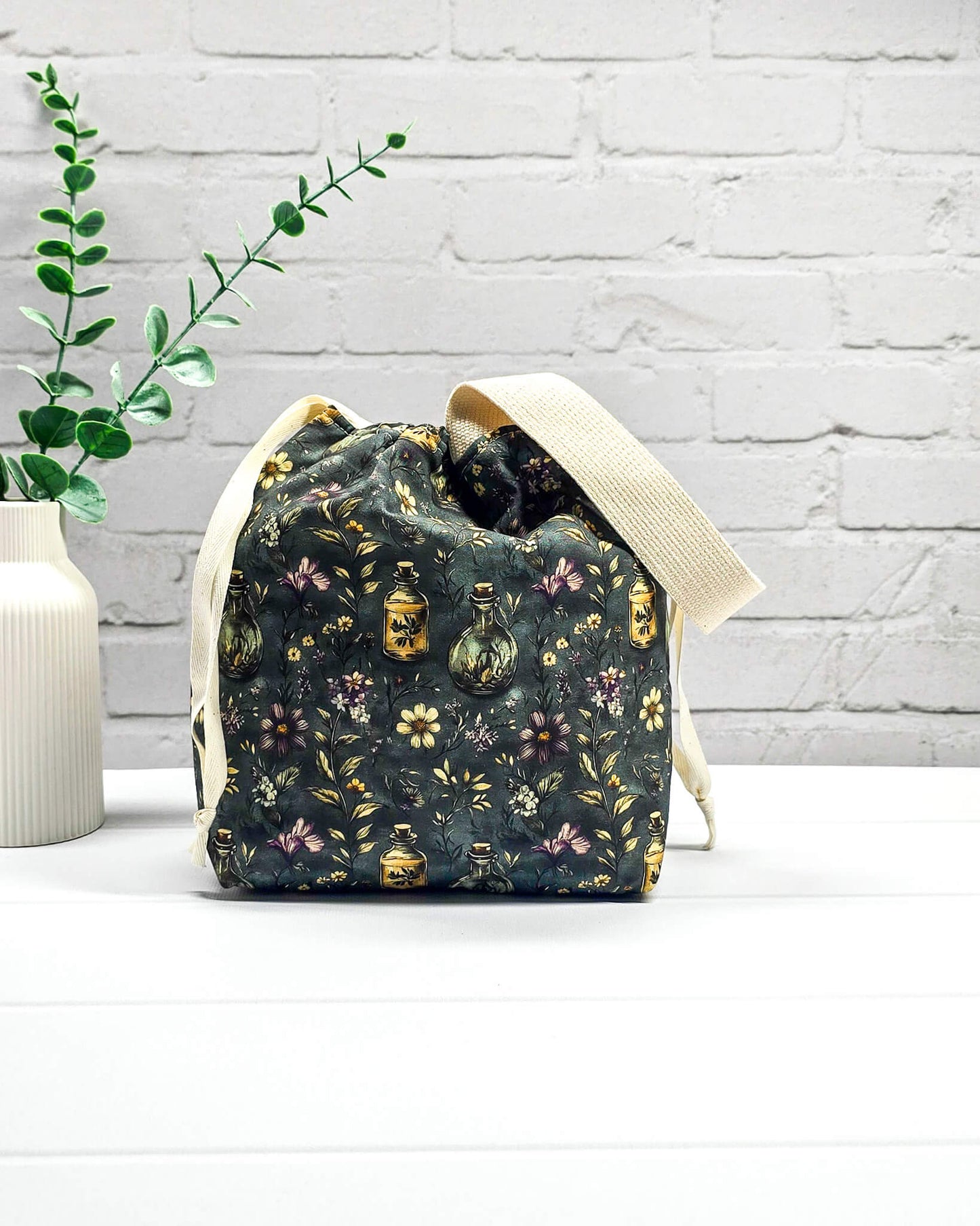 Stricktasche für bis zu 200 g Wolle im dunklen Botanical Apothecary Design mit Blüten und nostalgischen Apothekerfläschchen. Handgenäht in Bayern von NadelMikado.
