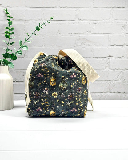 Stricktasche für bis zu 200 g Wolle im dunklen Botanical Apothecary Design mit Blüten und nostalgischen Apothekerfläschchen. Handgenäht in Bayern von NadelMikado.