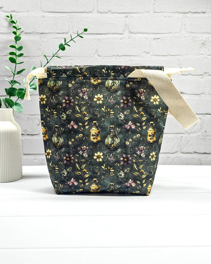 Stricktasche für bis zu 200 g Wolle im dunklen Botanical Apothecary Design mit Blüten und nostalgischen Apothekerfläschchen. Handgenäht in Bayern von NadelMikado.