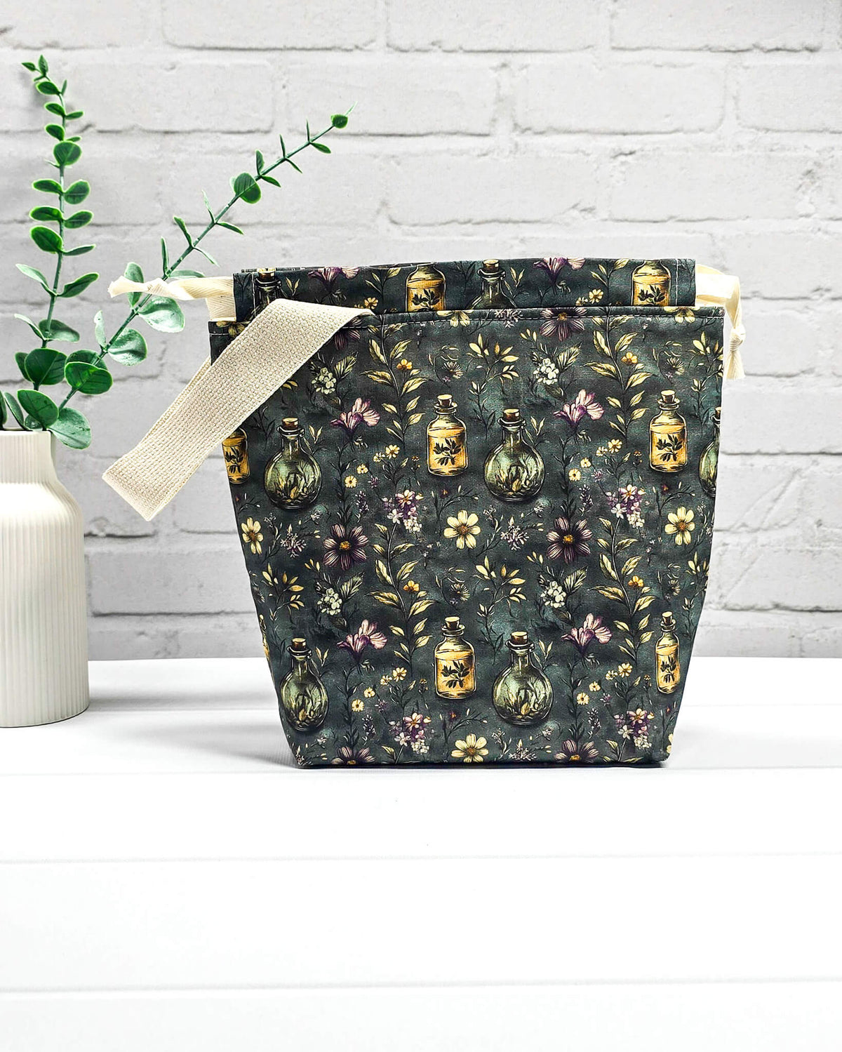 Stricktasche für bis zu 200 g Wolle im dunklen Botanical Apothecary Design mit Blüten und nostalgischen Apothekerfläschchen. Handgenäht in Bayern von NadelMikado.
