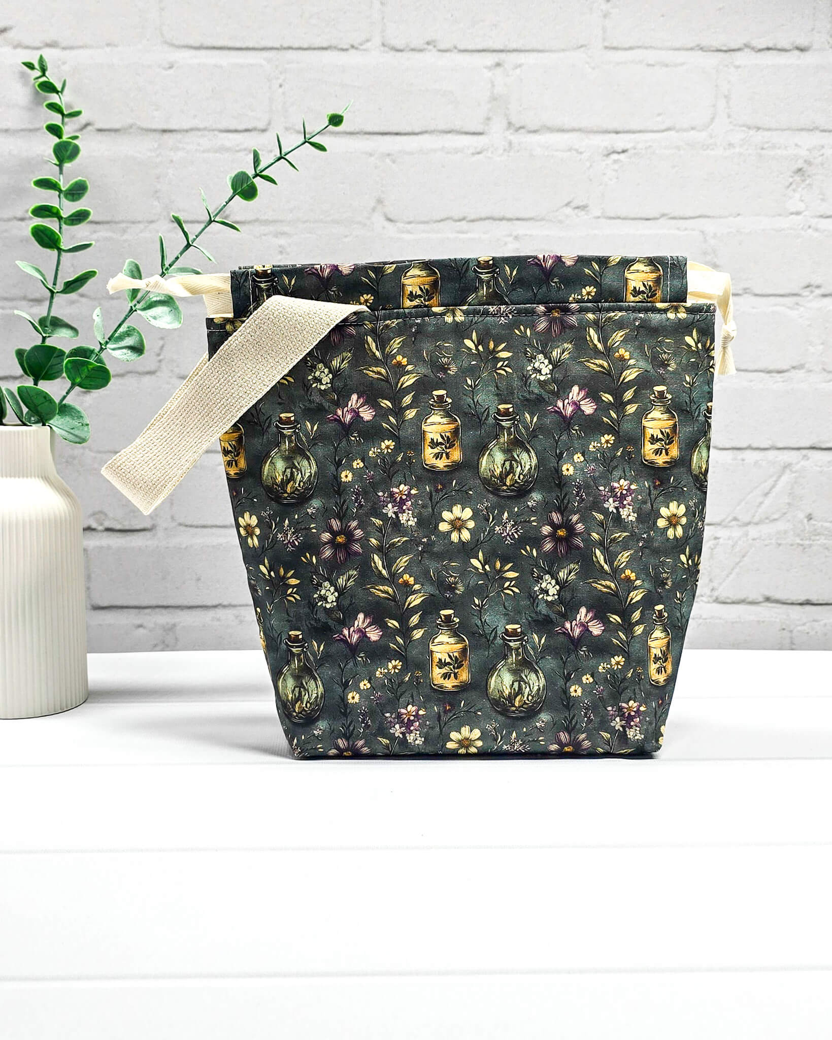 Stricktasche für bis zu 200 g Wolle im dunklen Botanical Apothecary Design mit Blüten und nostalgischen Apothekerfläschchen. Handgenäht in Bayern von NadelMikado.