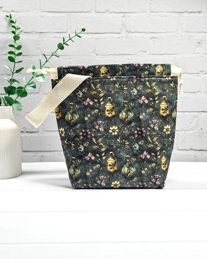 Stricktasche für bis zu 200 g Wolle im dunklen Botanical Apothecary Design mit Blüten und nostalgischen Apothekerfläschchen. Handgenäht in Bayern von NadelMikado.
