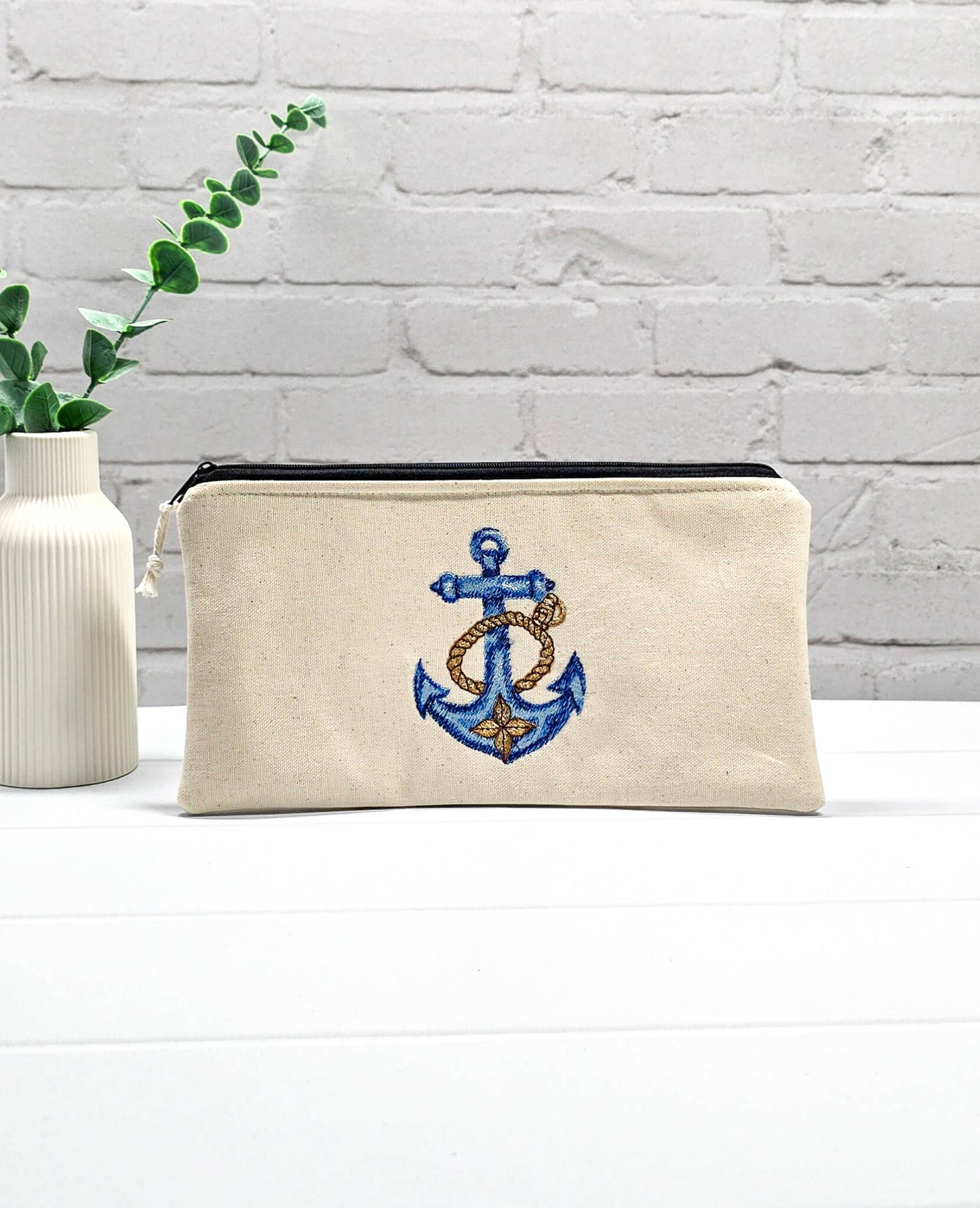 Flache, rechteckige Zip Pouch Runa aus beigem Canvas mit einem großen, blau-gold gestickten Schiffsanker, ideal um Stricknadeln, Seile und Scheren sicher zu verwahren. Handgenäht in Bayern von Nadelmikado