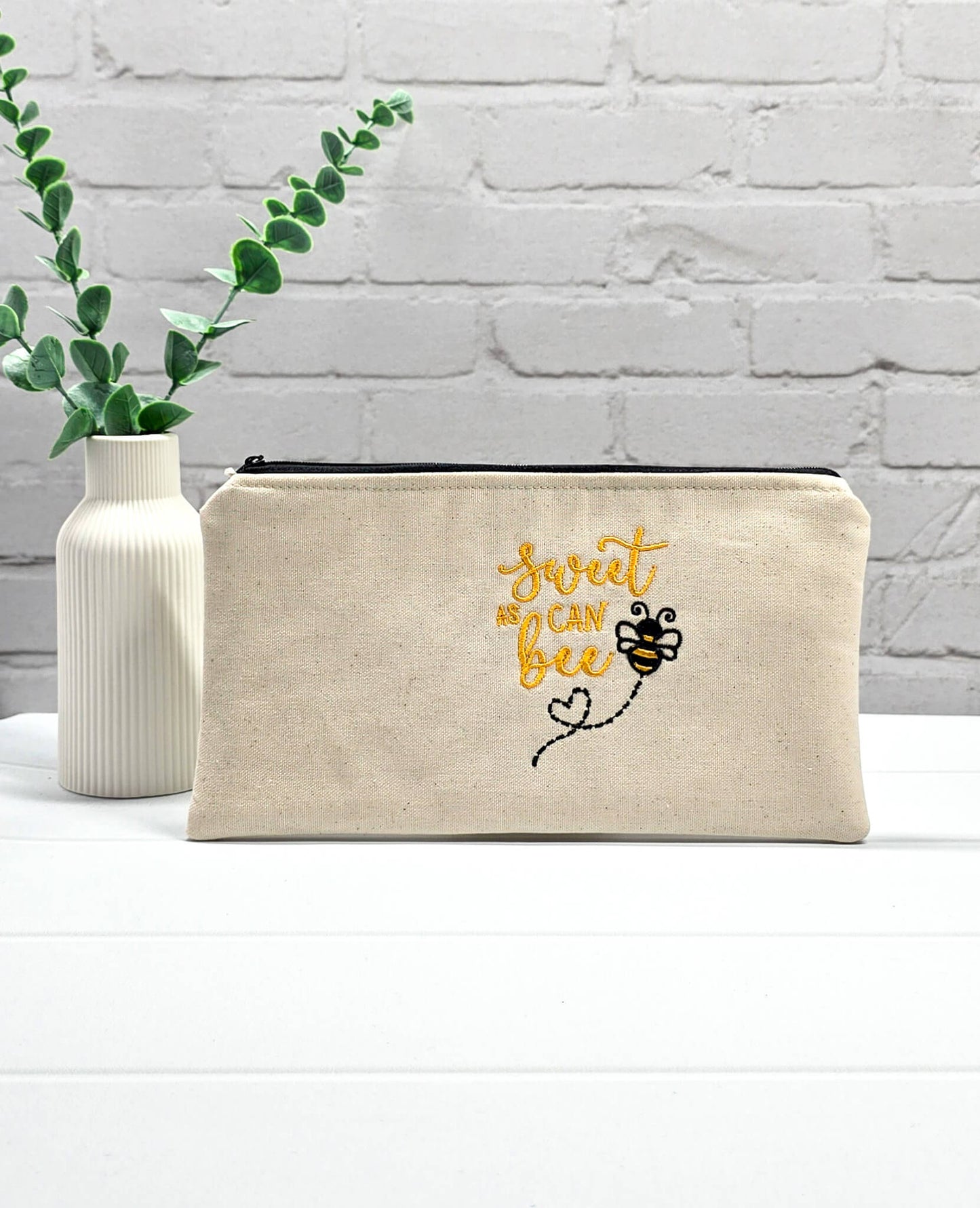 Flache, rechteckige Zip Pouch Runa aus beigem Canvas mit gestickter Biene und gelbem Schriftzug, handgenäht in Bayern von Nadelmikado