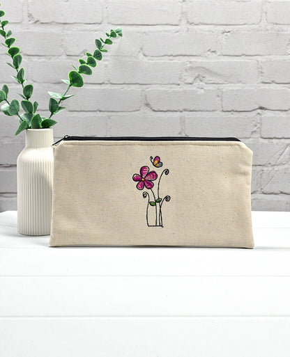 Flache, rechteckige Zip Pouch Runa aus beigem Canvas mit einer zierlich gestickten Blume und einem Schmetterling, perfekt zum geschützten Aufbewahren von Stricknadeln und Zubehör. Handgenäht in Bayern von Nadelmikado.