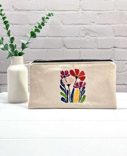 Flache, rechteckige Zip Pouch Runa aus beigem Canvas mit einer großen, bunt gestickten Blumengruppe, ideal zum platzsparenden Einsortieren von Stricknadeln und Seilen. Handgenäht in Bayern von Nadelmikado.