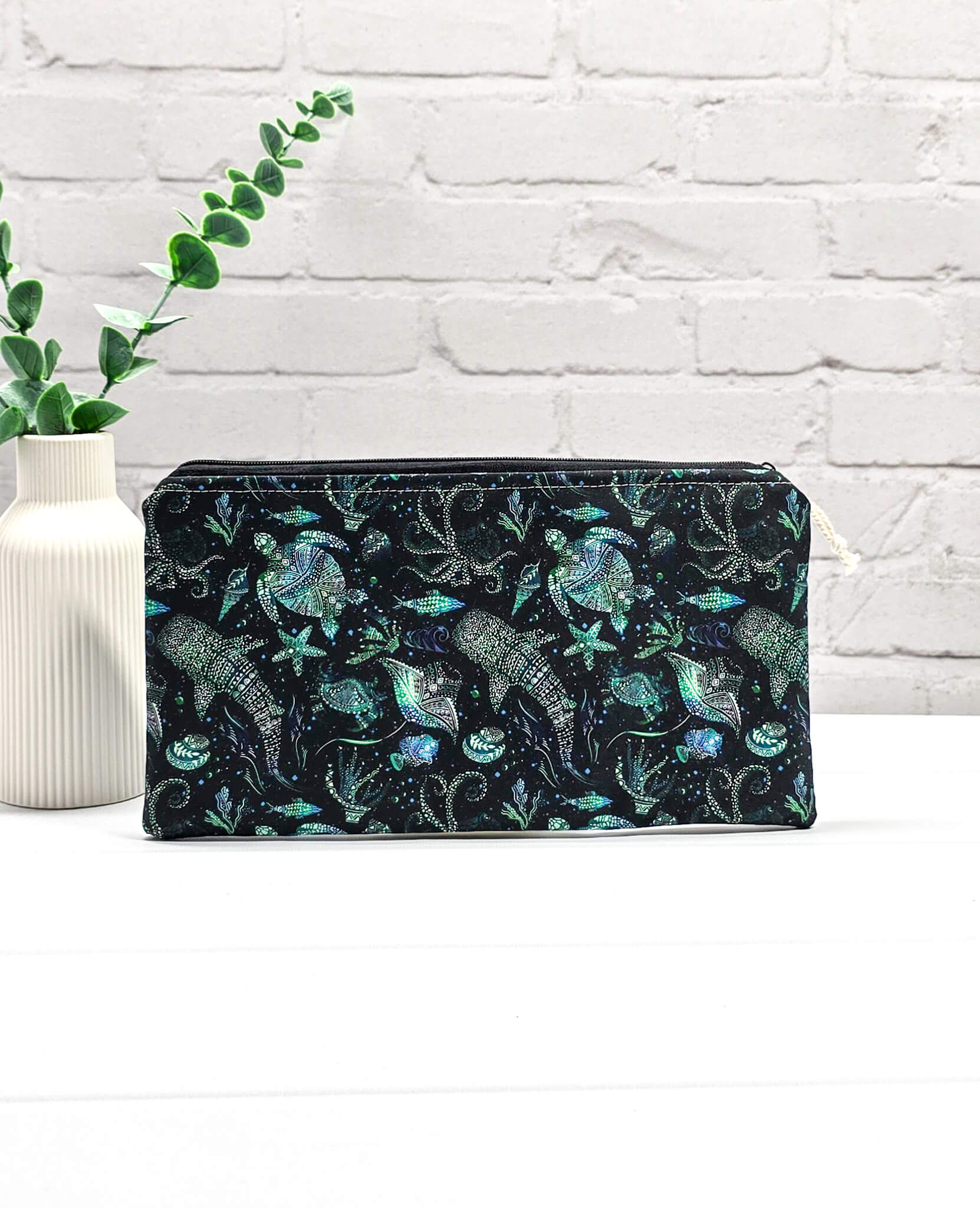 Flache, rechteckige Zip Pouch Runa aus schwarzem Stoff mit leuchtend grün-blauen Meerestieren, handgenäht in Bayern von Nadelmikado