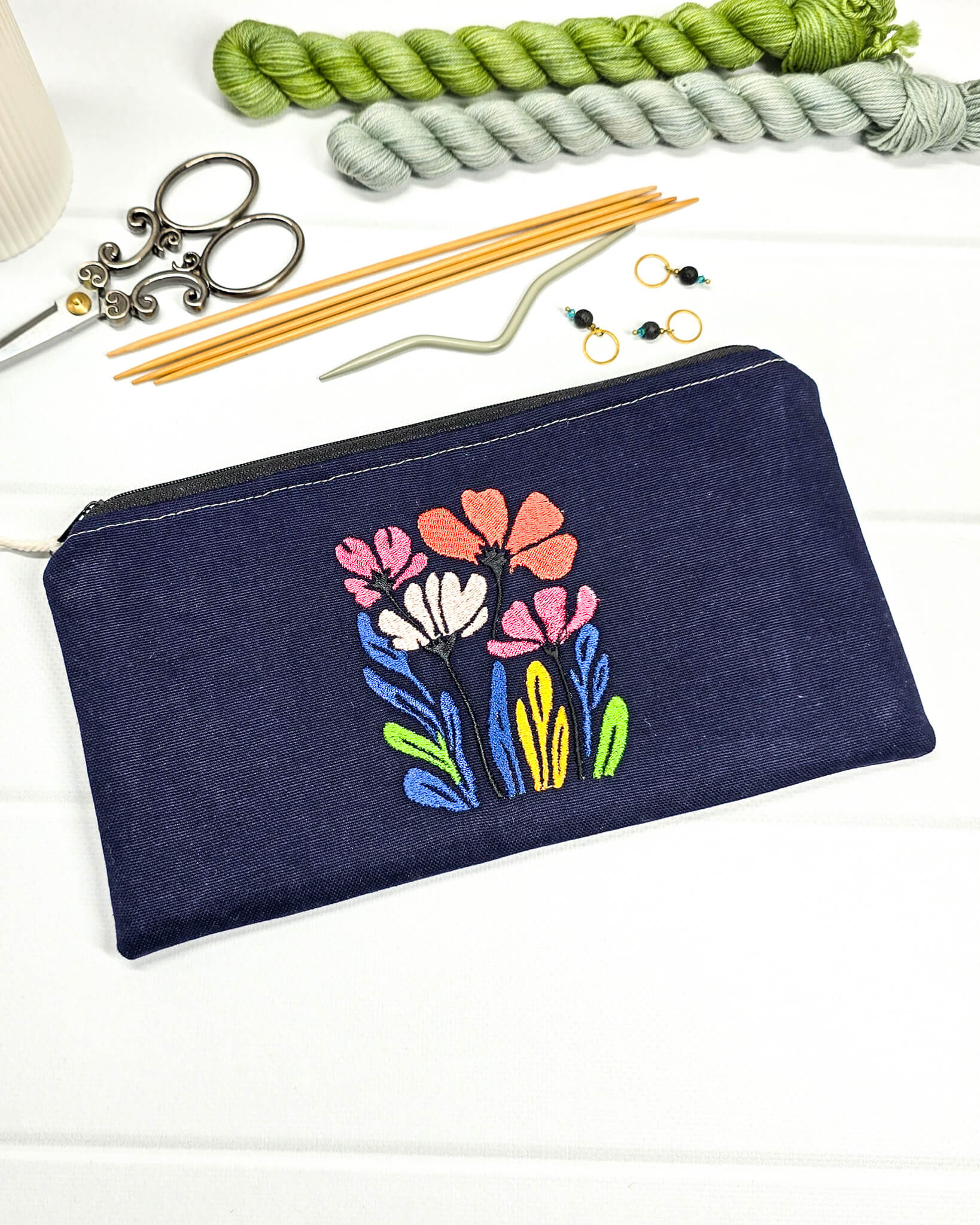 Dunkelblaues Stoff-Etui Runa mit einer farbenfrohen, dichten Wildblumen-Stickerei, ideal um empfindliche Nadelseile und Häkelnadeln vor dem Verheddern zu schützen. Handgenäht in Bayern von Nadelmikado.