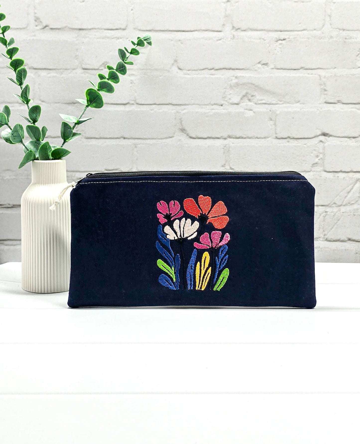 Dunkelblaues Stoff-Etui Runa mit einer farbenfrohen, dichten Wildblumen-Stickerei, ideal um empfindliche Nadelseile und Häkelnadeln vor dem Verheddern zu schützen. Handgenäht in Bayern von Nadelmikado.
