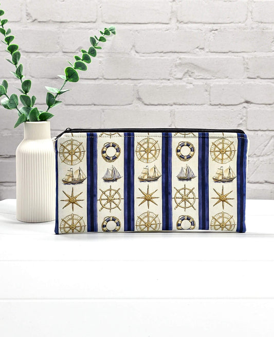Flache, rechteckige Zip Pouch Runa mit maritimen Motiven wie Segelschiffen und Steuerrädern zwischen blau-weißen Streifen, handgenäht in Bayern von Nadelmikado. 